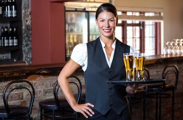 Portrait of waitress holding serving tray with two glass of beer