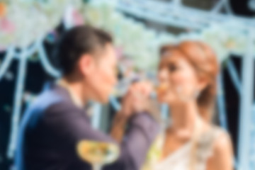 blurred Couple lover with arms crossed to drink wine in wedding