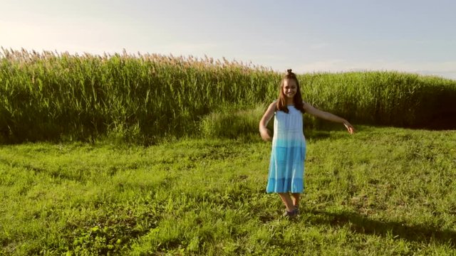 Young teenage girl dances outdoors in a green meadow during sunset full HD