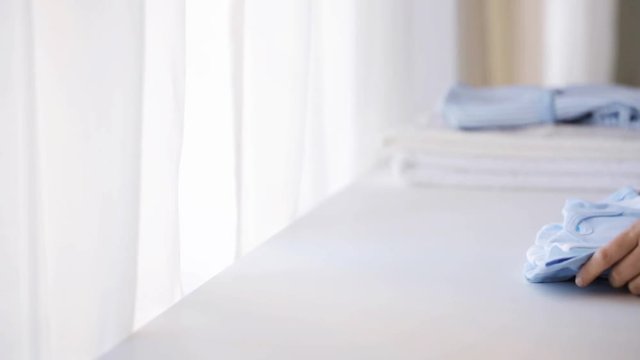 woman hand putting bootees on baby boys clothes 24