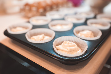 Obraz na płótnie Canvas Raw dough for cupcake in baking tray closeup. Selective focus.
