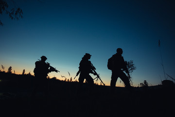 Fototapeta na wymiar Silhouette of military soldiers with weapons at night. shot,