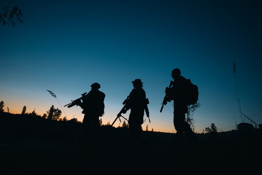 Silhouette of military soldiers with weapons at night. shot, hol