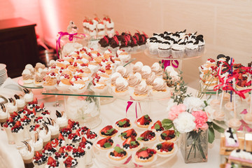 Delicious and tasty dessert table with cupcakes shots at reception closeup