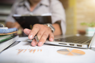 business man hand working on laptop computer with digital layer business graph information diagram on wooden desk as concept