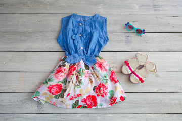 Beautiful dress, sandal and sunglasses on a white wooden backgro