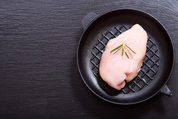 fresh chicken breast with rosemary in a pan