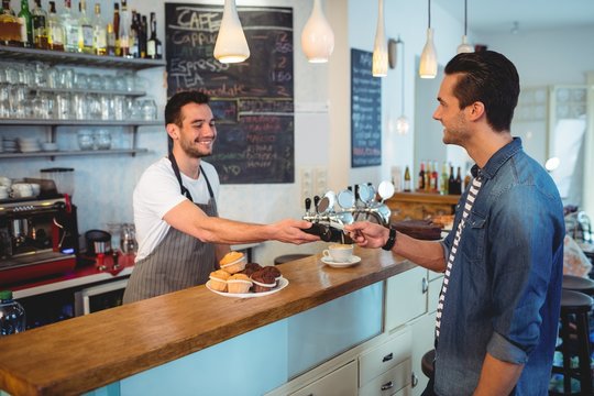 Happy customer paying through credit card at coffee shop