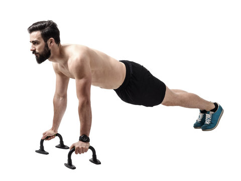 Shirtless muscular athlete doing push-up on push up bars. Full body length portrait isolated over white studio background.