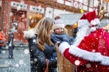 Little toddler girl with mother on Christmas market. 