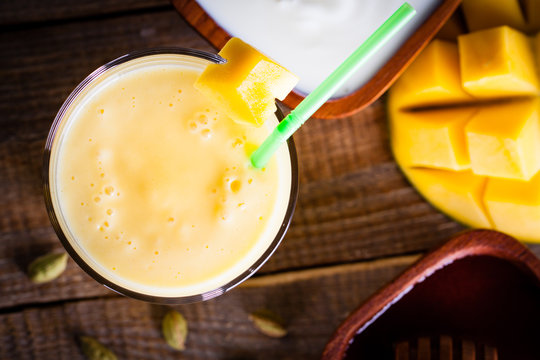 Overhead, glass of milkshake made of mango and yoghurt with sweet honey.