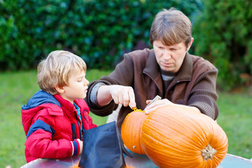 Father and little kid boy making halloween pumpkin