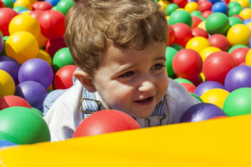 Fototapeta na wymiar Baby boy having fun playing in a colorful plastic ball pool