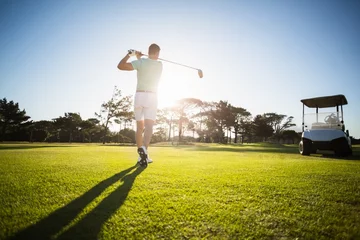 Fotobehang Golf Achteraanzicht van mannelijke golfspeler die schot neemt