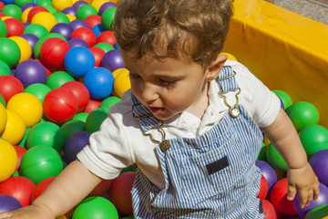 Baby boy having fun playing in a colorful plastic ball pool