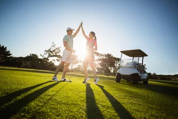 Keuken foto achterwand Golf Gelukkig golfspelerpaar die high five geven