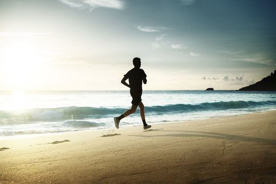 Man Running On Tropical Beach At Sunset