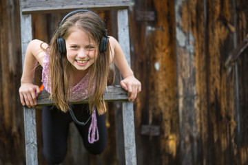 Little naughty girl with headphones outdoors.