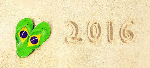 Brazilian colored flip flops and 2016 written on the beach