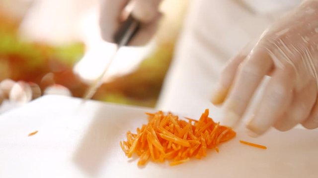 Kitchen knife cuts carrot. Pile of shredded carrot. Ingredient for salad is ready. Clean cooking board.