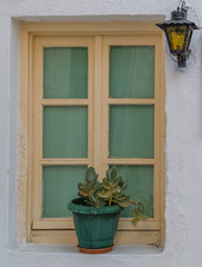 Lantern on the white wall near flower kalanchoe in pot on windowsill