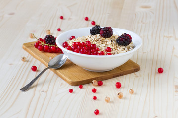 Oatmeal with berries and a glass of fresh milk on a wooden table, a healthy breakfast. Concept diet food.