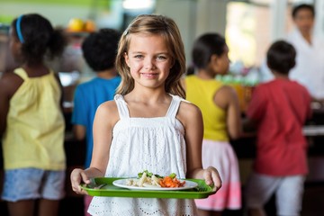 Schoolgirl holding tray in canteen 