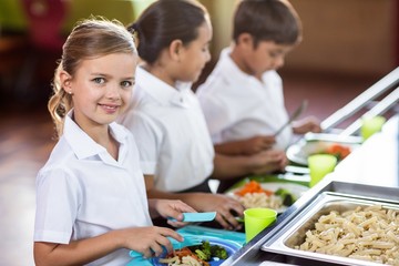 Fototapeta premium Schoolgirl with classmate standing near canteen counter