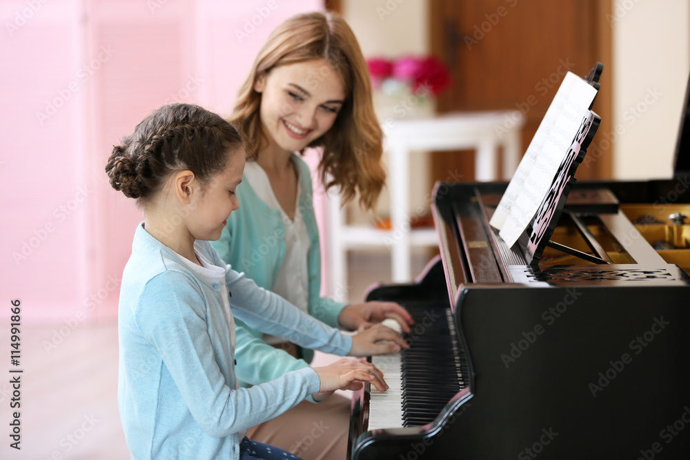 Wall mural small girl learning play piano with teacher