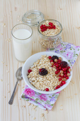 Oatmeal with berries and a glass of fresh milk on a wooden table, a healthy breakfast. 