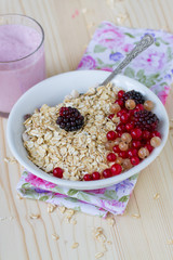 Porridge with berries and a cup of yogurt on a wooden table , a healthy breakfast