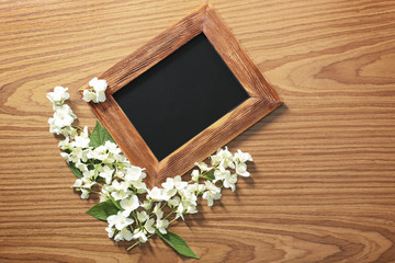 Empty frame and fresh jasmine flowers on wooden background
