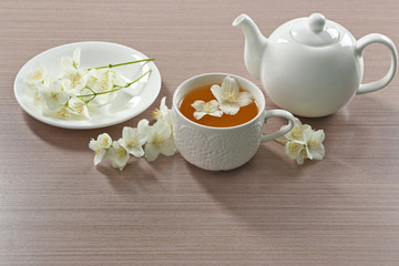 Cup of tea with jasmine flowers on wooden background