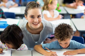 Portrait of happy female teacher helping schoolchildren