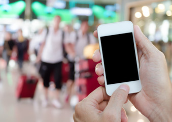 Hands holding smartphone with blurred background of people at airport arrival.