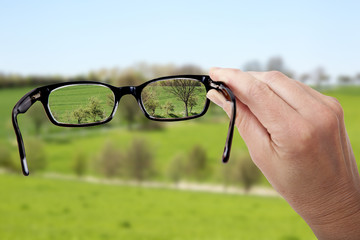 Hand holding glasses to see clearly