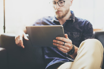 Bearded marketing specialist working digital tablet modern Interior Design Loft Office.Man relax classic sofa use contemporary device Hand.Blurred Background New creative Process Business Startup Idea