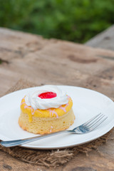 Butter cake with strawberry jam and whipped cream on wooden table