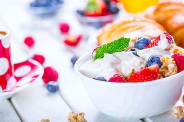 Muesli with yogurt and berries on a wooden table. Healthy fruit and cereal brakfast.