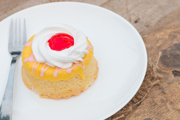 Butter cake with strawberry jam and whipped cream on wooden table