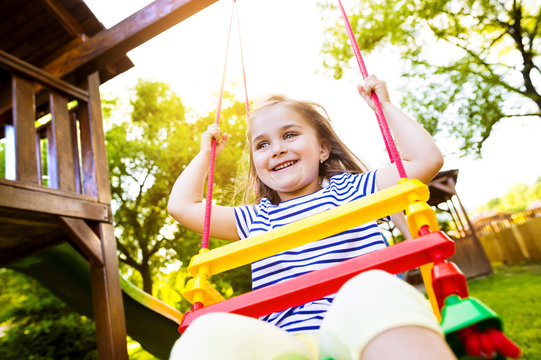Portrait of happy little girl on a swing