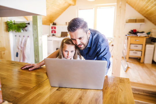 Father and daughter using laptop at home