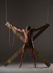 Sexual naked man, muscular, hands tied rope to wooden beams