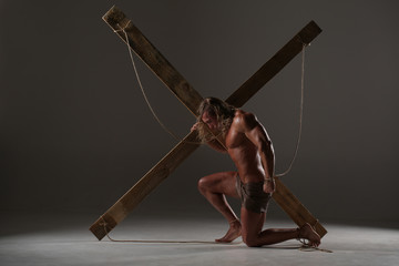 Sexual naked man, muscular, hands tied rope to wooden beams