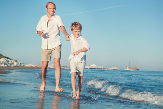 Father with son running together on the sea surf line