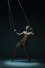 Young naked man, muscular body, bounded with rope