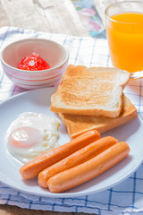 breakfast with fried eggs,sausage and toasts on wooden table