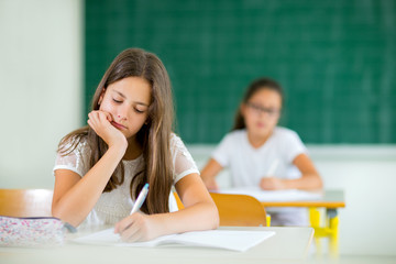 Portrait of two happy schoolgirls in a classroom, selective focus