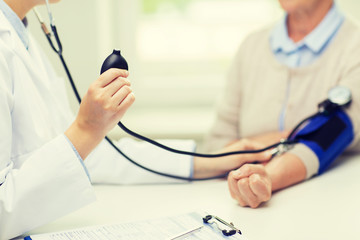 doctor with tonometer and senior woman at hospital