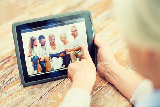 senior woman with family photo on tablet pc screen